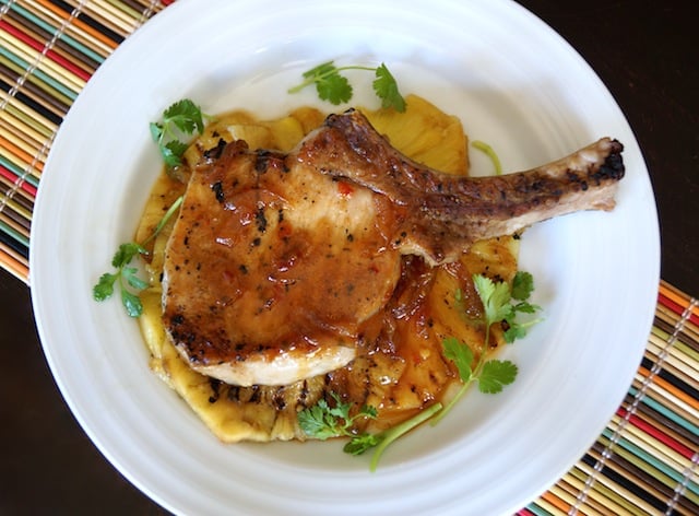 Sweet and Spicy Pineapple Pork Chop on a white plate with cilantro sprigs.
