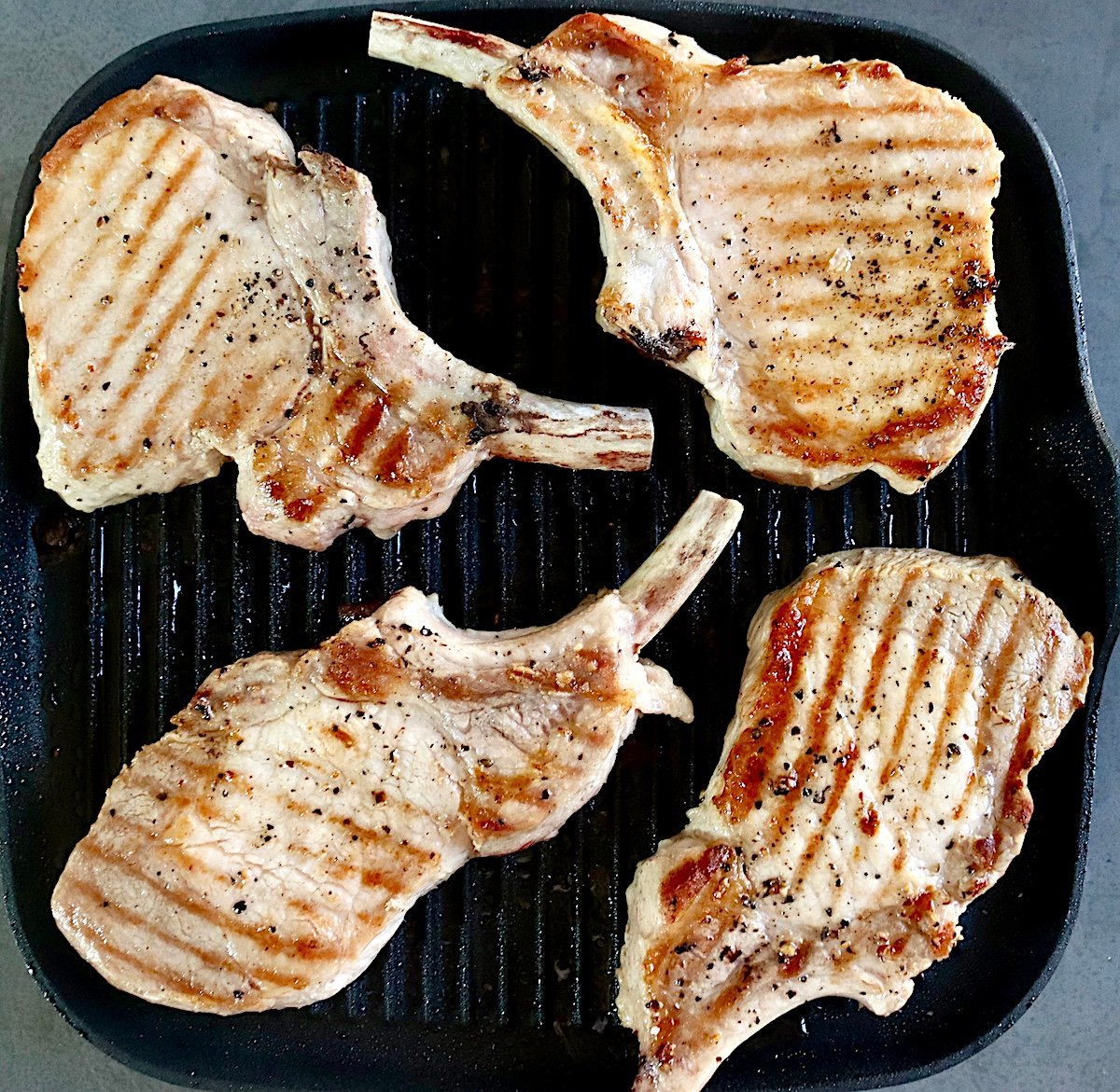 4 grilled pork chops on a grill.