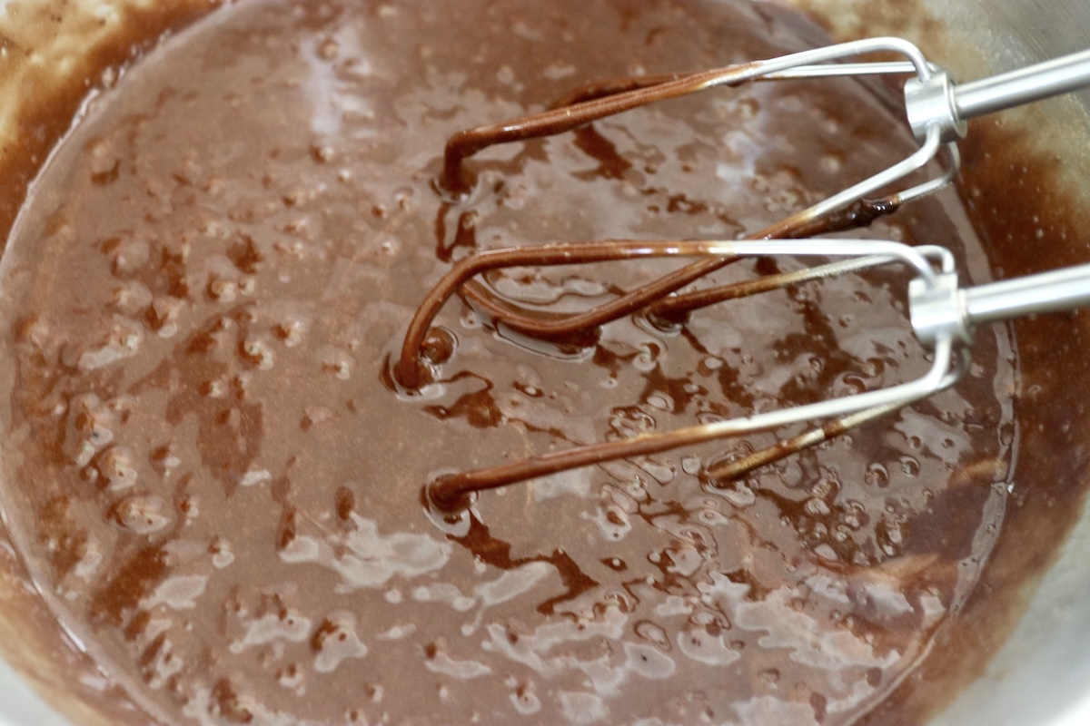 Chocolate brownie batter with electric mixer beaters.