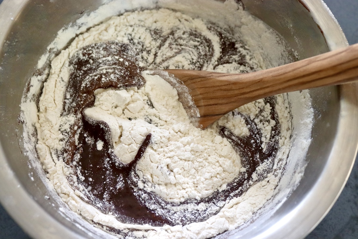 Chocolate brownie batter - being mixed with flour, with a wooden spoon.