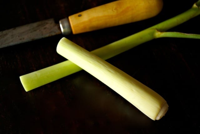 stalk of lemongrass halved on black background with a knife