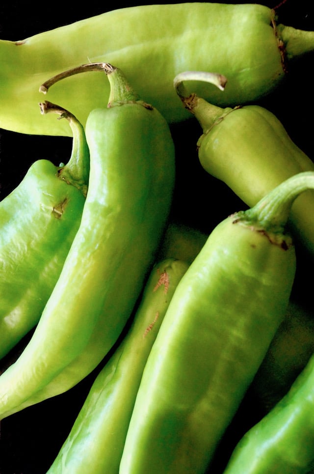 pile of bright green hatch chiles on black background