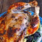 whole roasted blackberry chicken on a blue plate