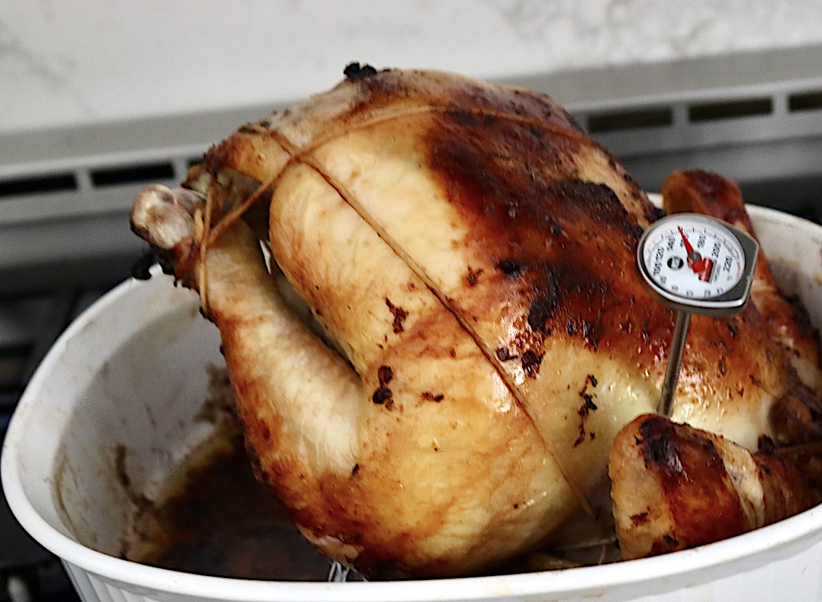 Blackberry-Chicken-Recipe-with-Blackberry-Butter) Whole roasted chicken with thermometer in the side with twine and foil beneath it.