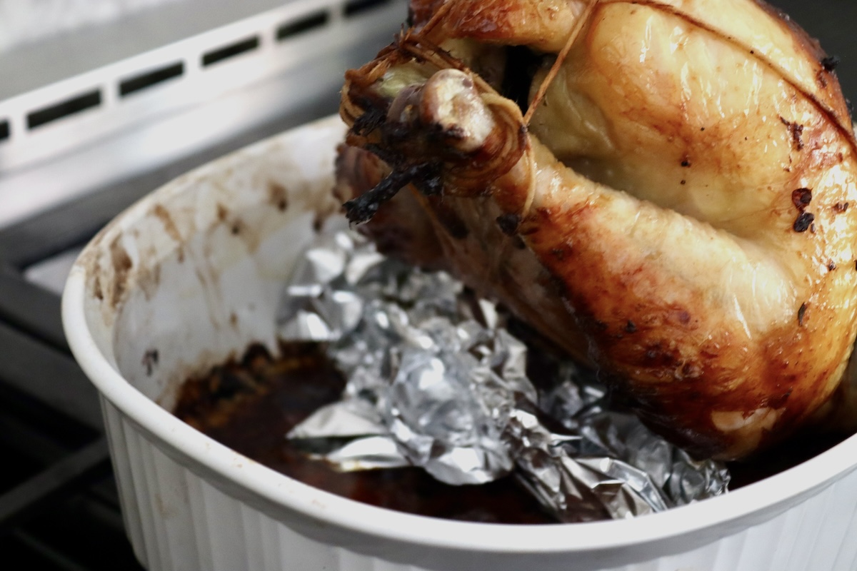 Blackberry-Chicken-Recipe-with-Blackberry-Butter) Whole roasted chicken with twine and foil beneath it.