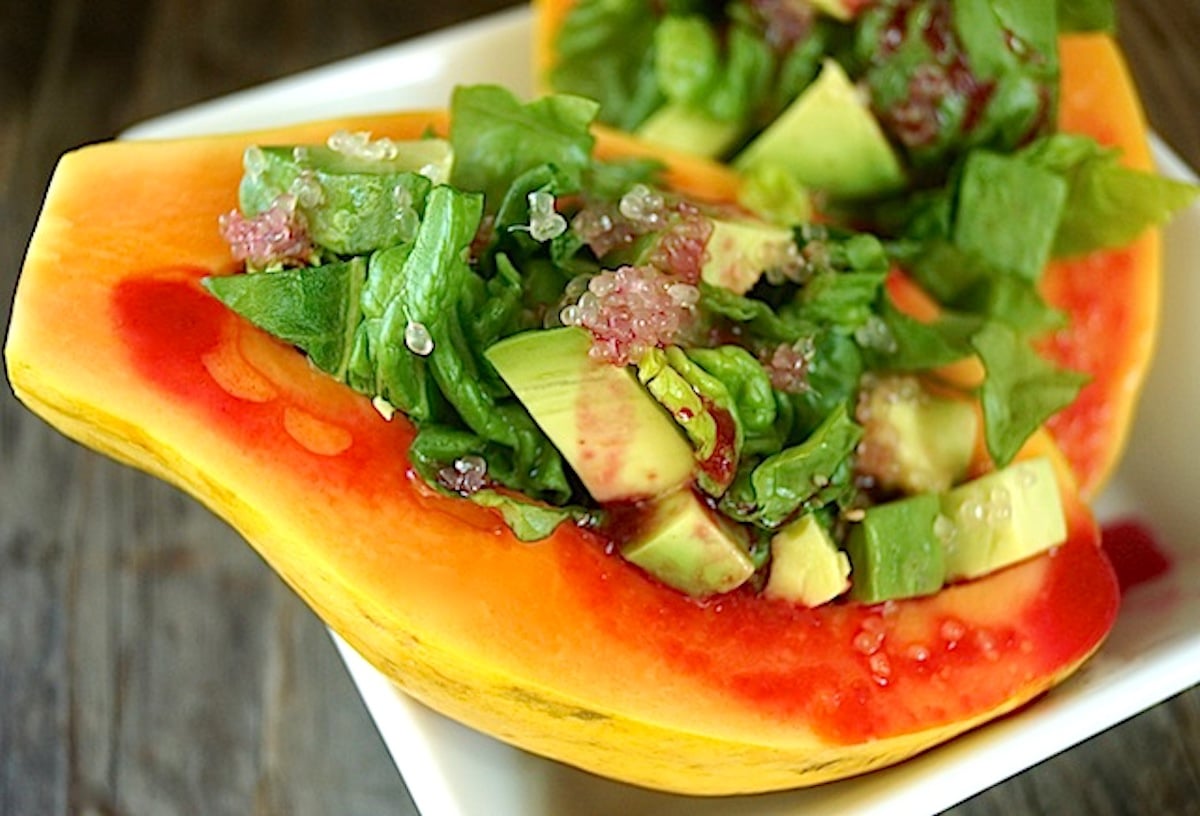 Papaya Salad with Avocado in a papaya half with reddish dressing.