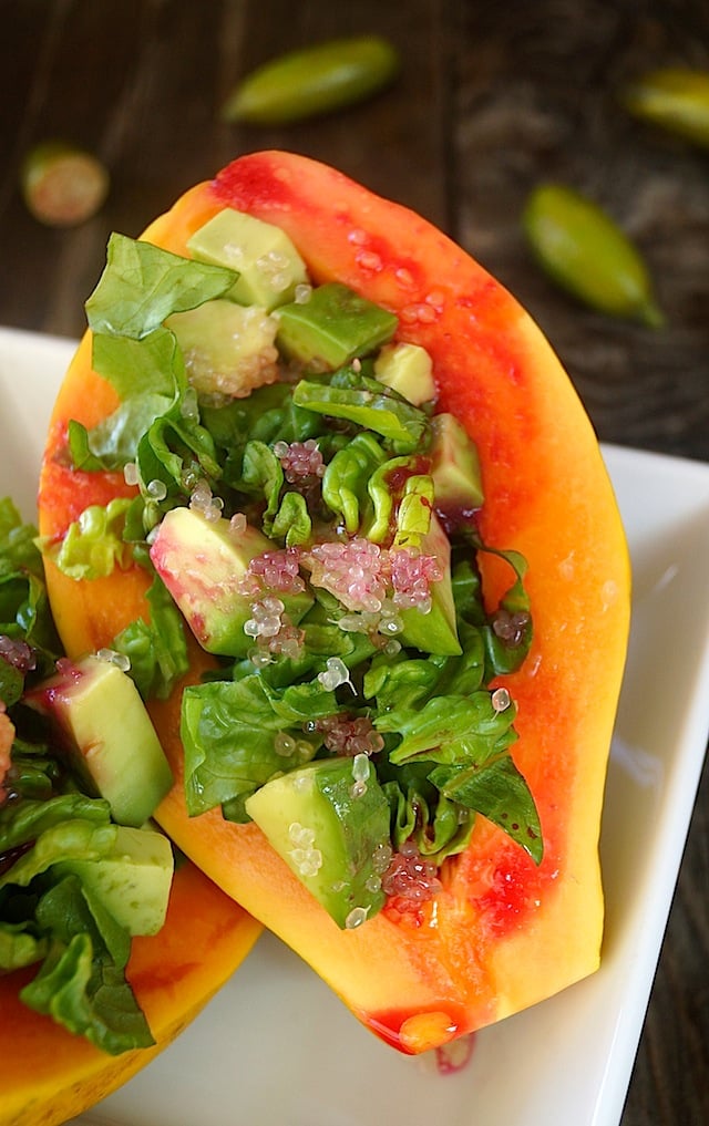 Papaya Salad with Avocado and Prickly Pear Vinaigrette in papaya halfon a white dish.