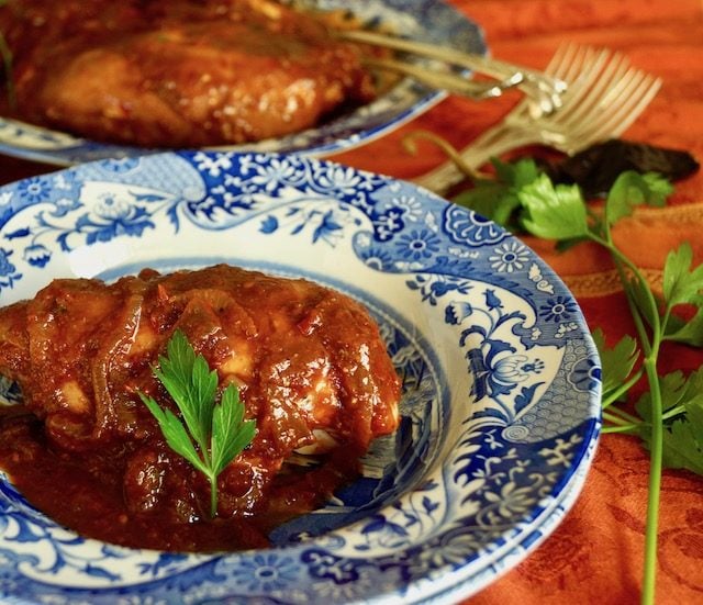 Chicken with brown-red sauce on a blue and white plate