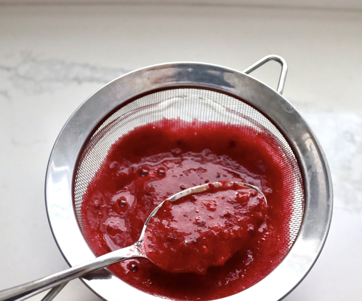 Prickly pear (cactus pear) pulp in a strainer with a spoon.