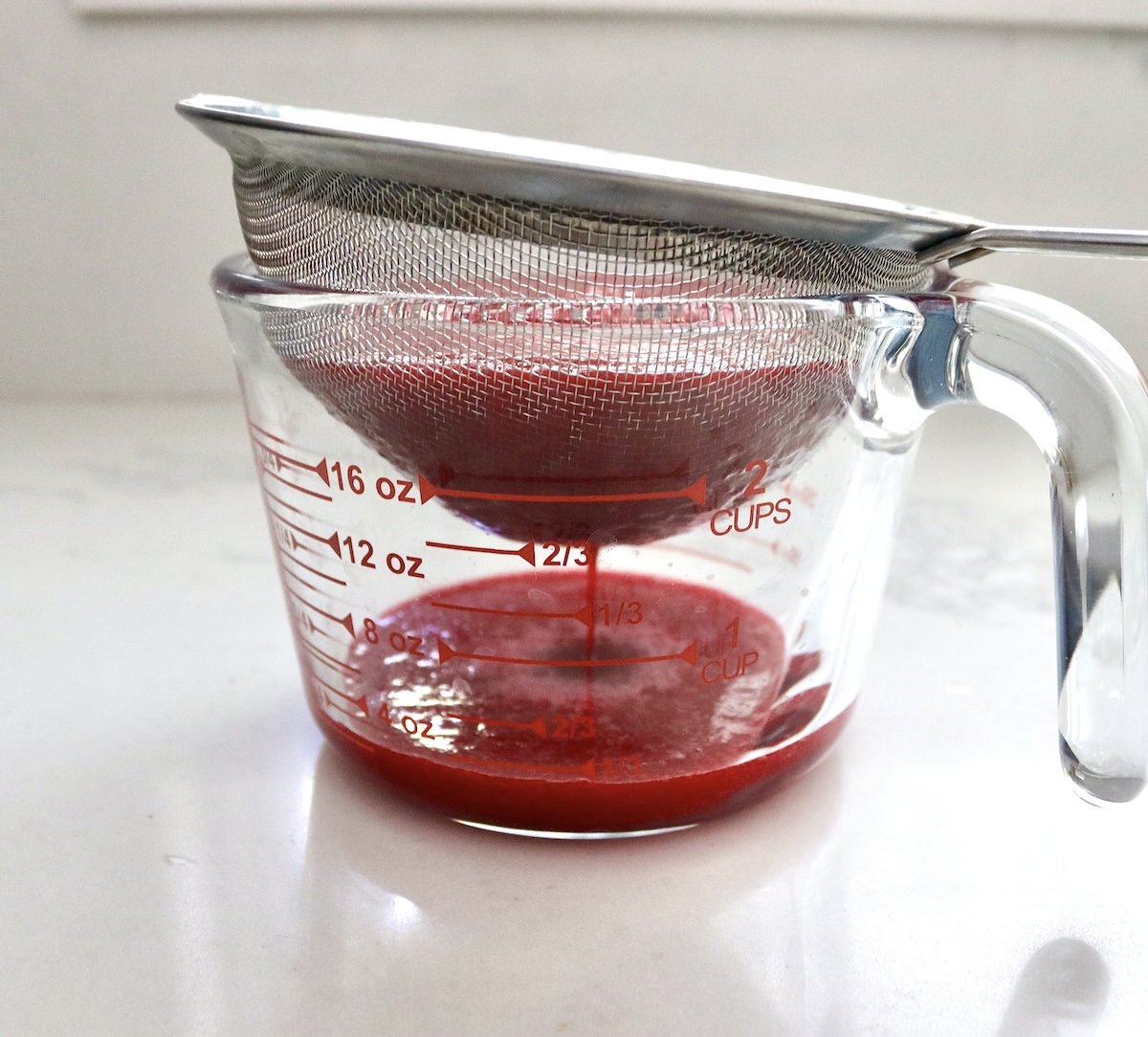 Prickly pear pulp being strained to removed seeds, into a glass 4 cup measure.