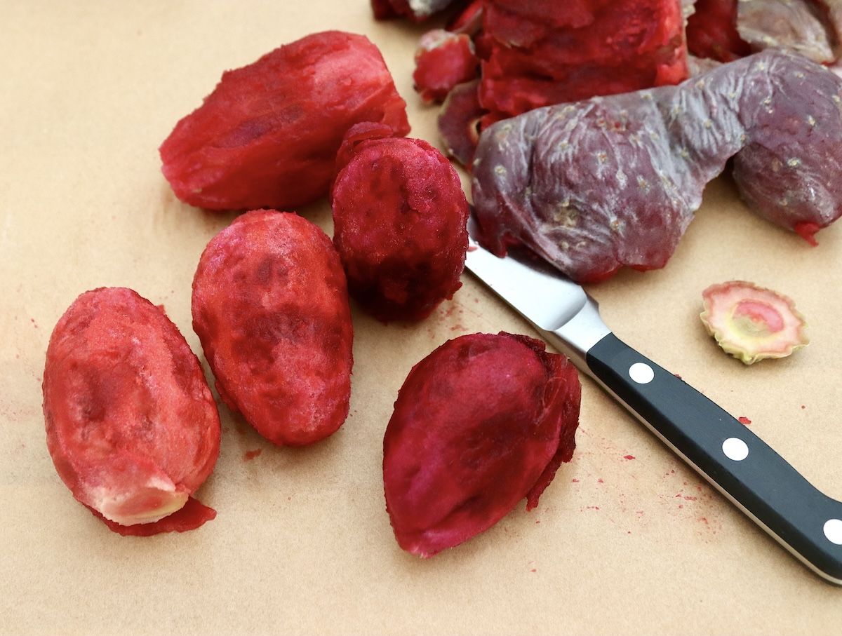 Prickly-Pear-Syrup Several peeled cactus pears (prickly pears) on a cutting board with skins and a paring knife next to them.