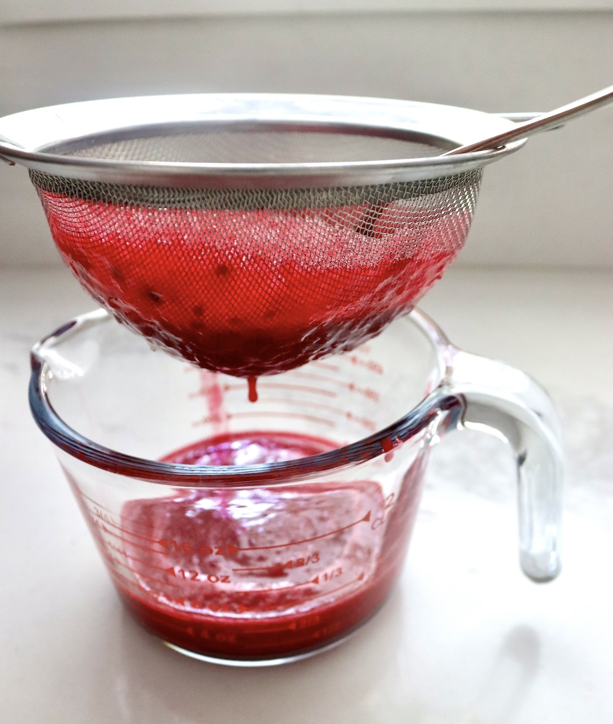 Prickly-Pear-Syrup Prickly pear pulp being strained into a glass 4 cup measure.