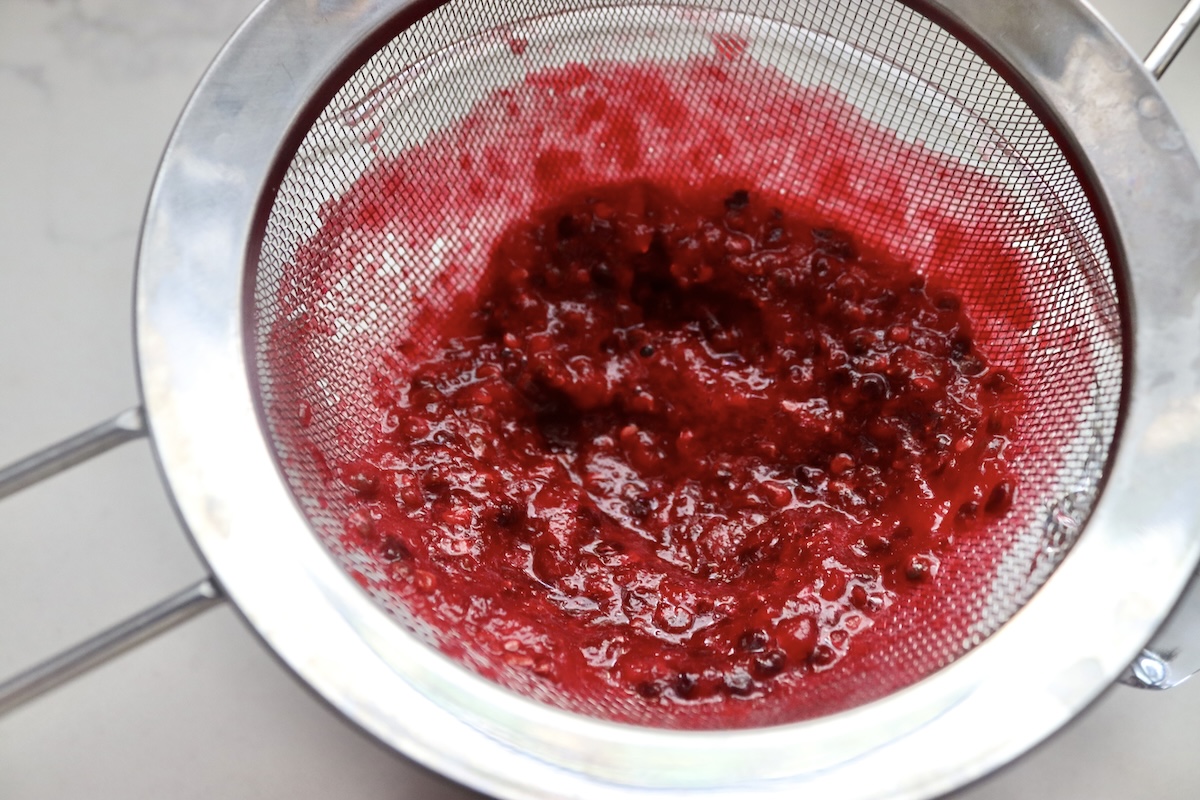 A strainer full with prickly pear fruit pulp and seeds.
