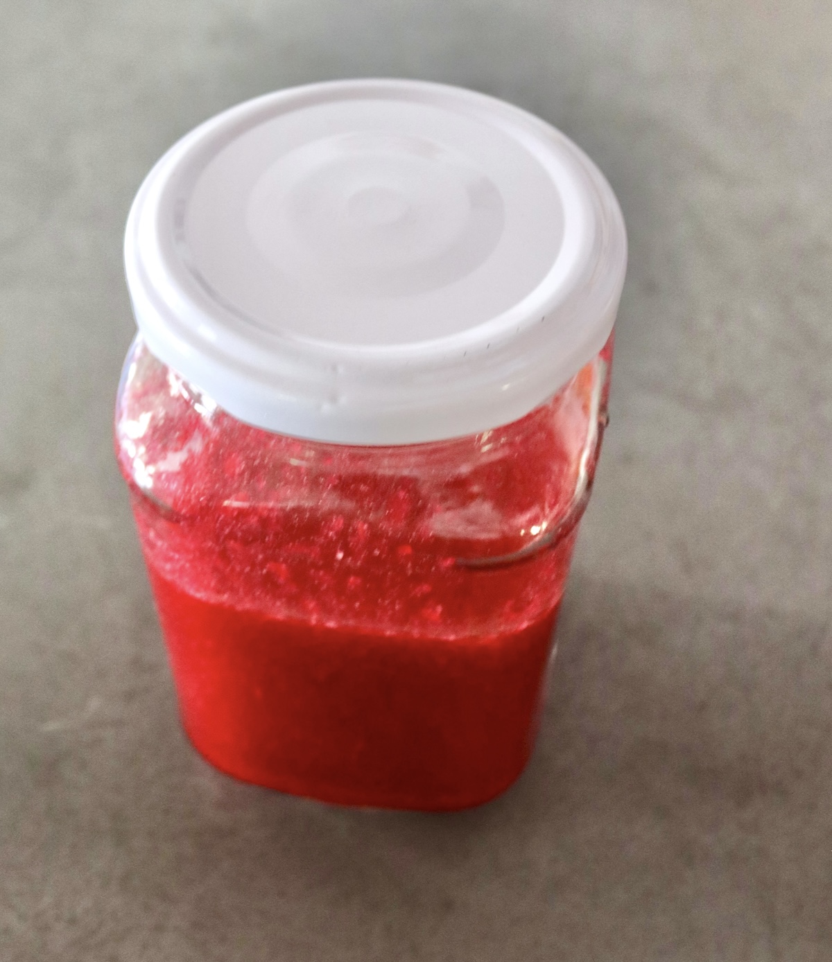 Prickly-Pear-Vinaigrette Jar about half full with prickly pear vinaigrette with a white lid.