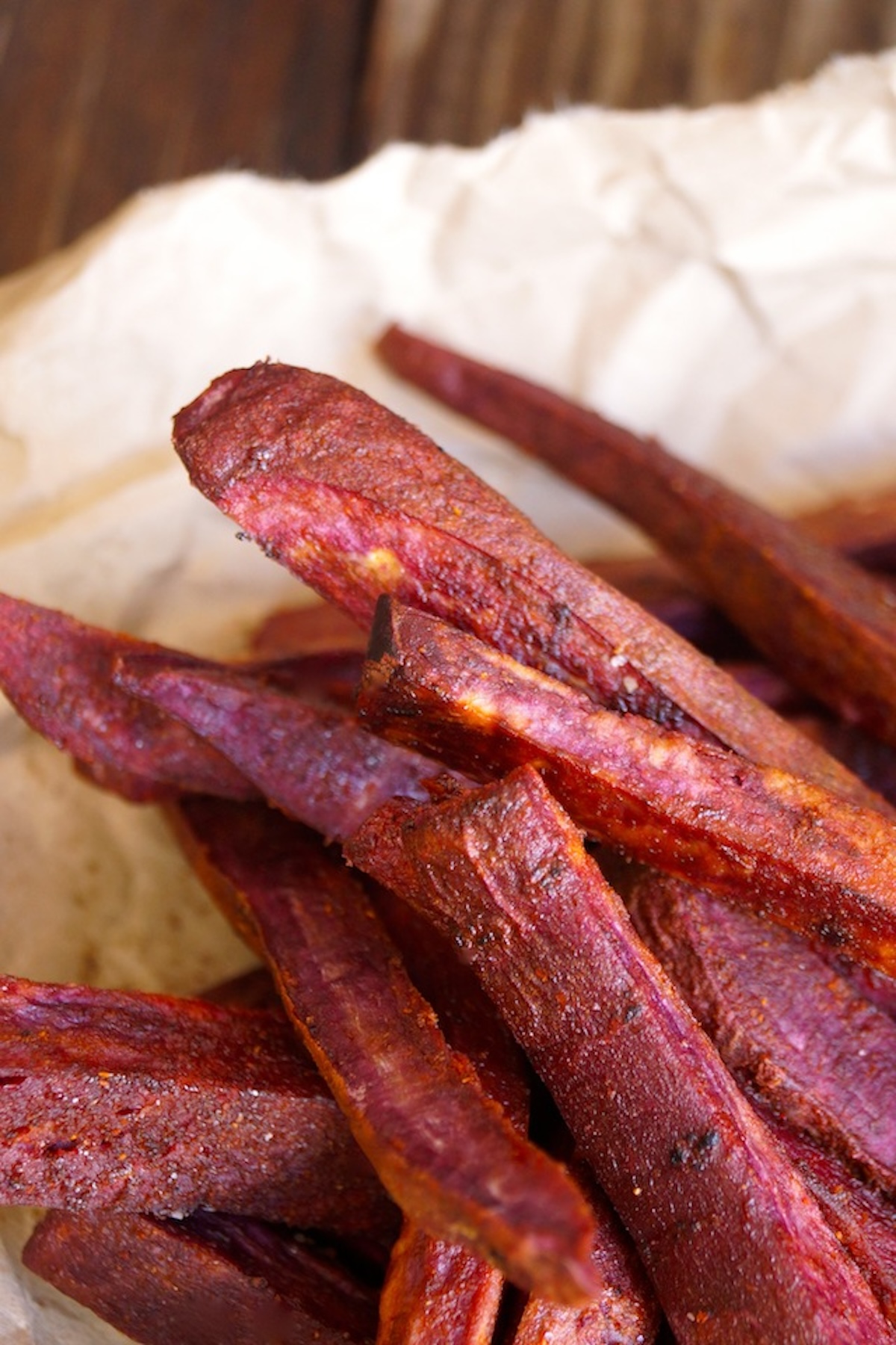 Close up of a small pile of purple French fries on crumpled parchment.