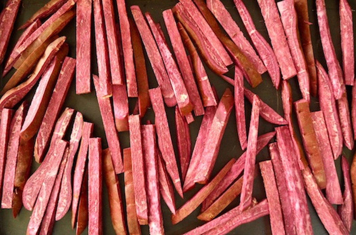Roasted Purple Sweet Potatoes cut into sticks on sheet pan.