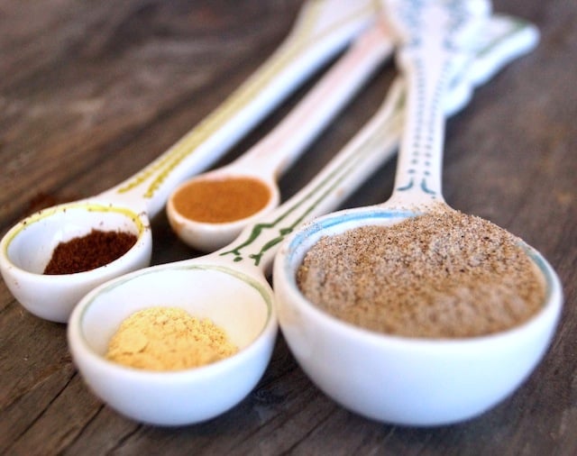 chai spices in white measureing spoons