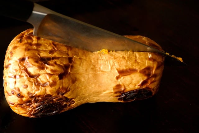 whole roasted squash being sliced in half with Chef's knife