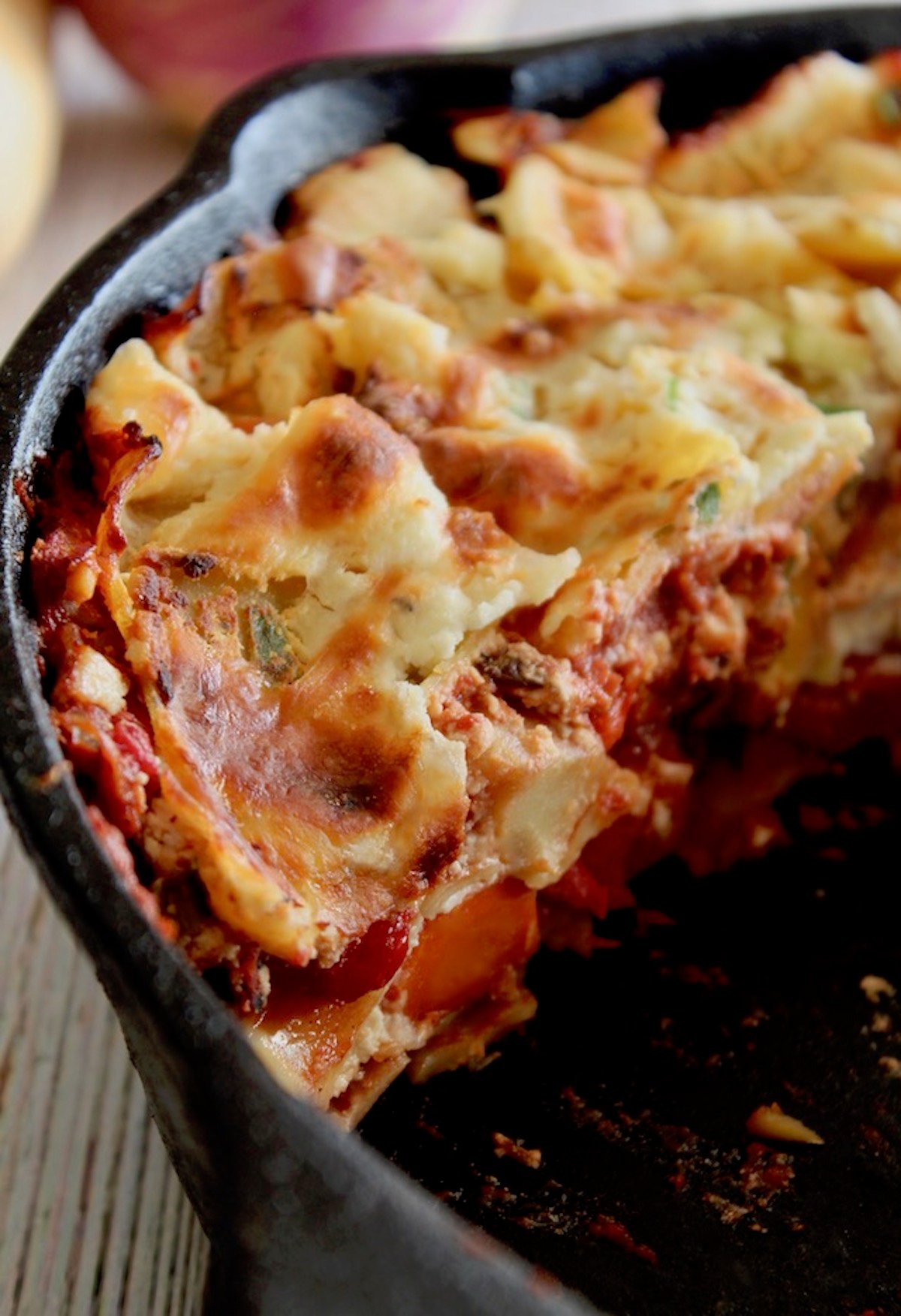 Half of a root vegetable lasagna in a cast iron skillet.
