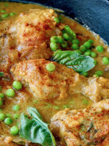 Sweet Potato Skillet Chicken with fresh peas and basil leaves on top, in cast iron skillet.