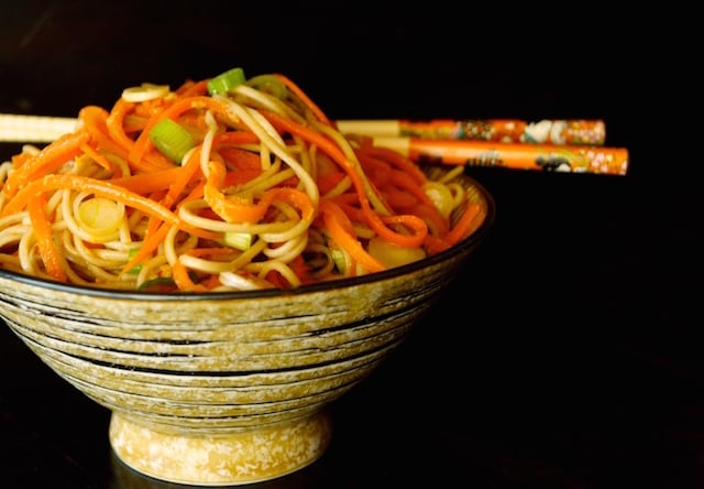 Carrot Ginger Soba Noodles with chopsticks in a brown bowl.