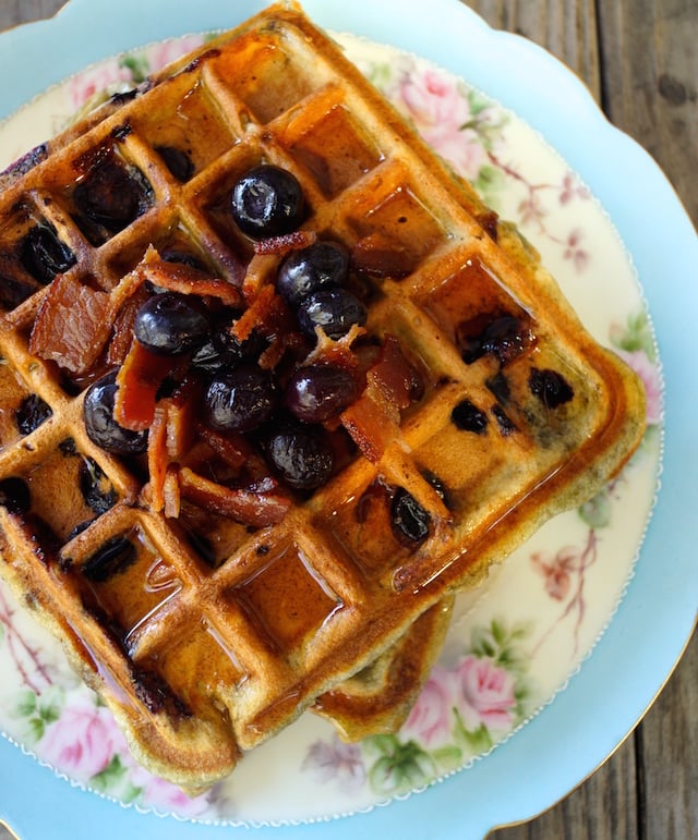 Brown Butter Blueberry Bacon waffles on a pretty, blue-rimmed plate