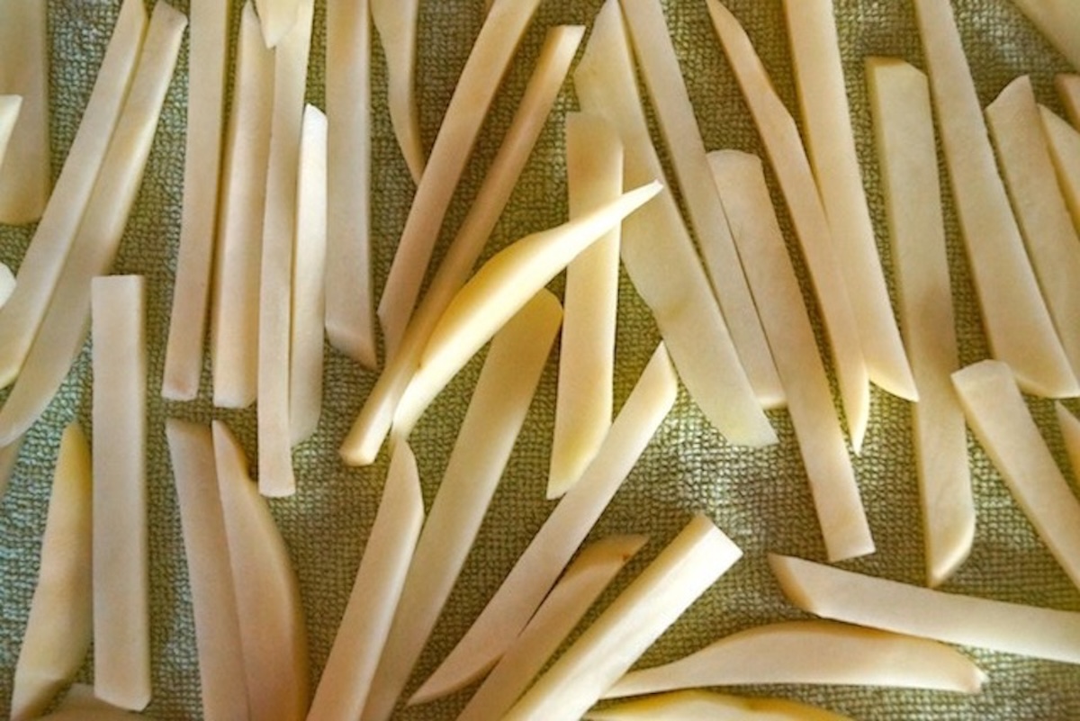Raw potato sticks on a light green kitchen towel.