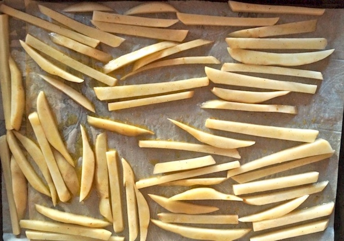 Raw potato sticks on parchment paper.