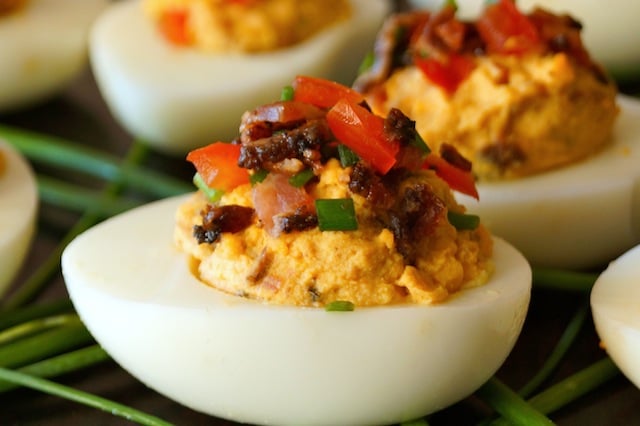 Close up of a Smoky Tomato-Bacon-Chipotle Deviled Egg with fresh chives