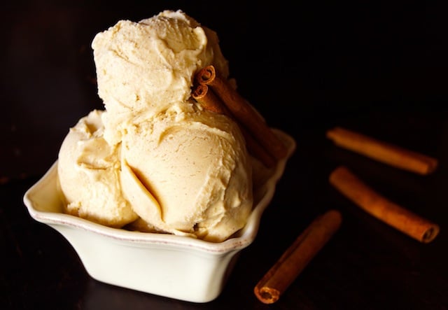 3 scoops of Cinnamon Ice Cream in square, cream-colored dish -- one cinnamon stick in the ice cream and three next to the dish.