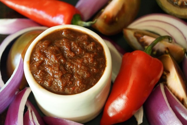 Small white bowl of Red Goddess Dressing and Sauce, surrounded by onion and peppers