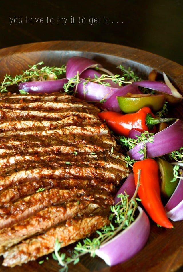 Red Goddess Grilled Flank Steak sliced thinly on a wooden platter