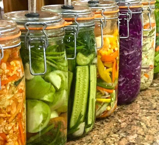 various vegetables fermenting in tall glass jars