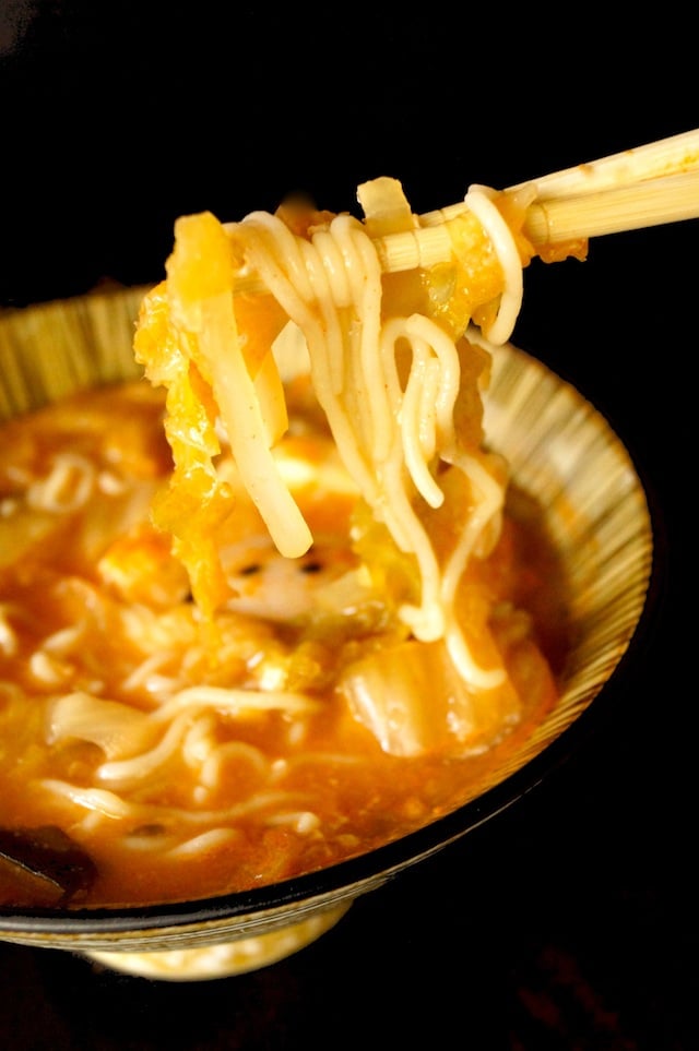 Kimchi Ramen Recipe with Egg, with a bite held by chopsticks.