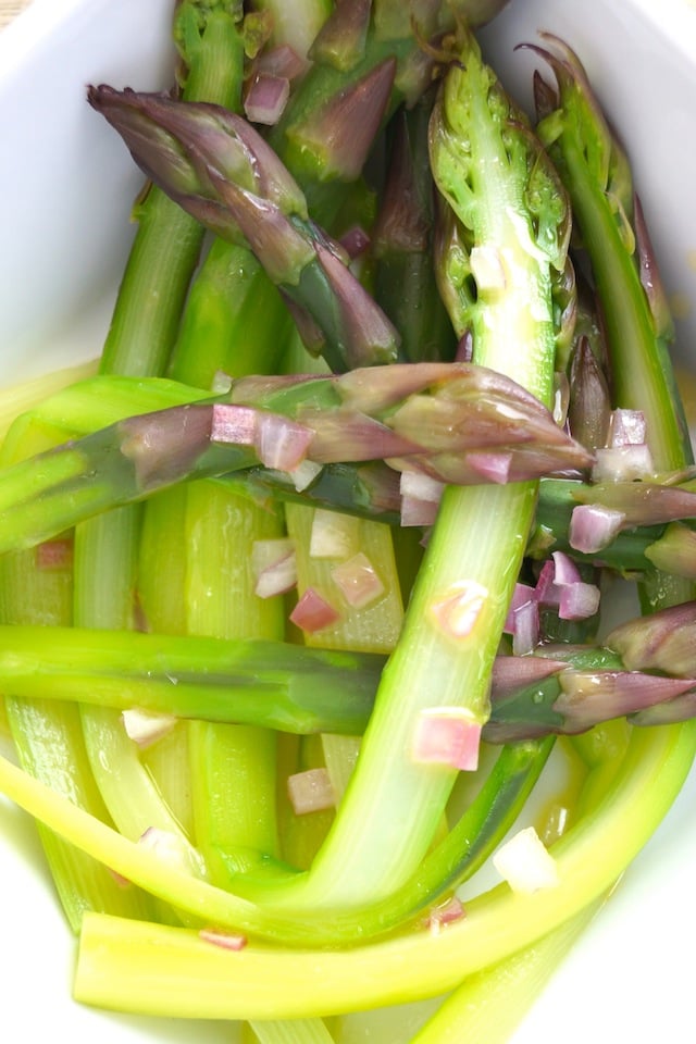 Peeled Purple Asparagus Recipe in a bright white dish with bits of shallots.