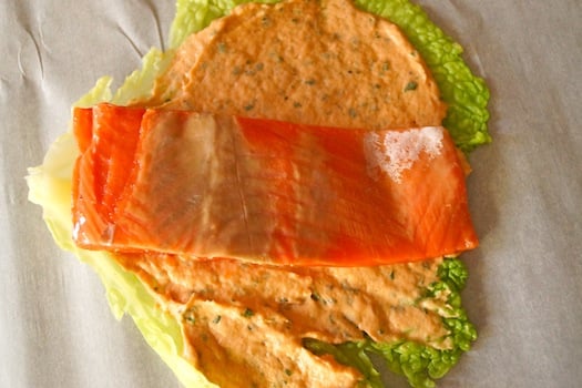 Prep for Cabbage Wrapped Salmon, with salmon fillet on top of cabbage leaf and salmon spread.