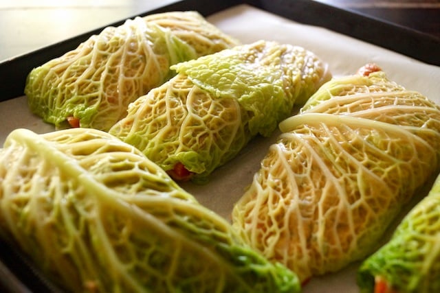 cabbage leaves wrapped abround salmon fillets on baking sheet.