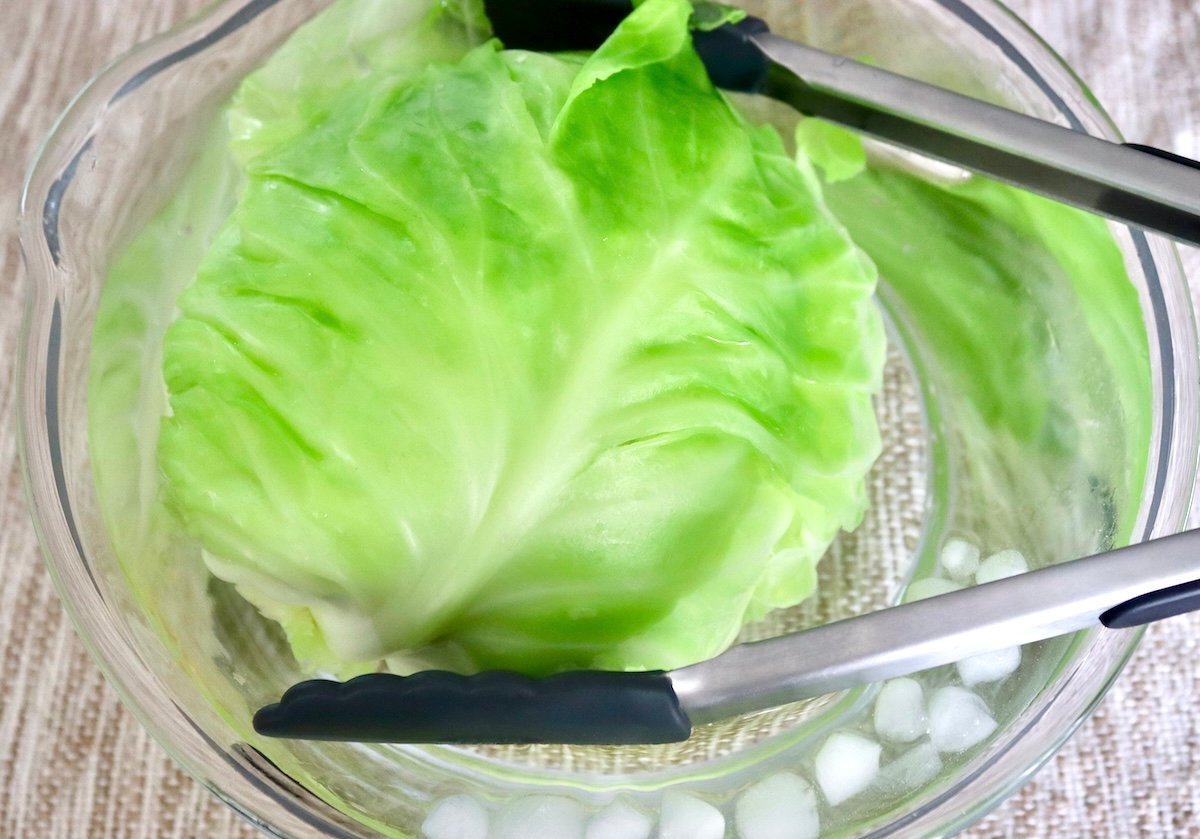 Salmon-and-Cabbage-Recipe Large glass bowl of ice water and green cabbage with tongs.