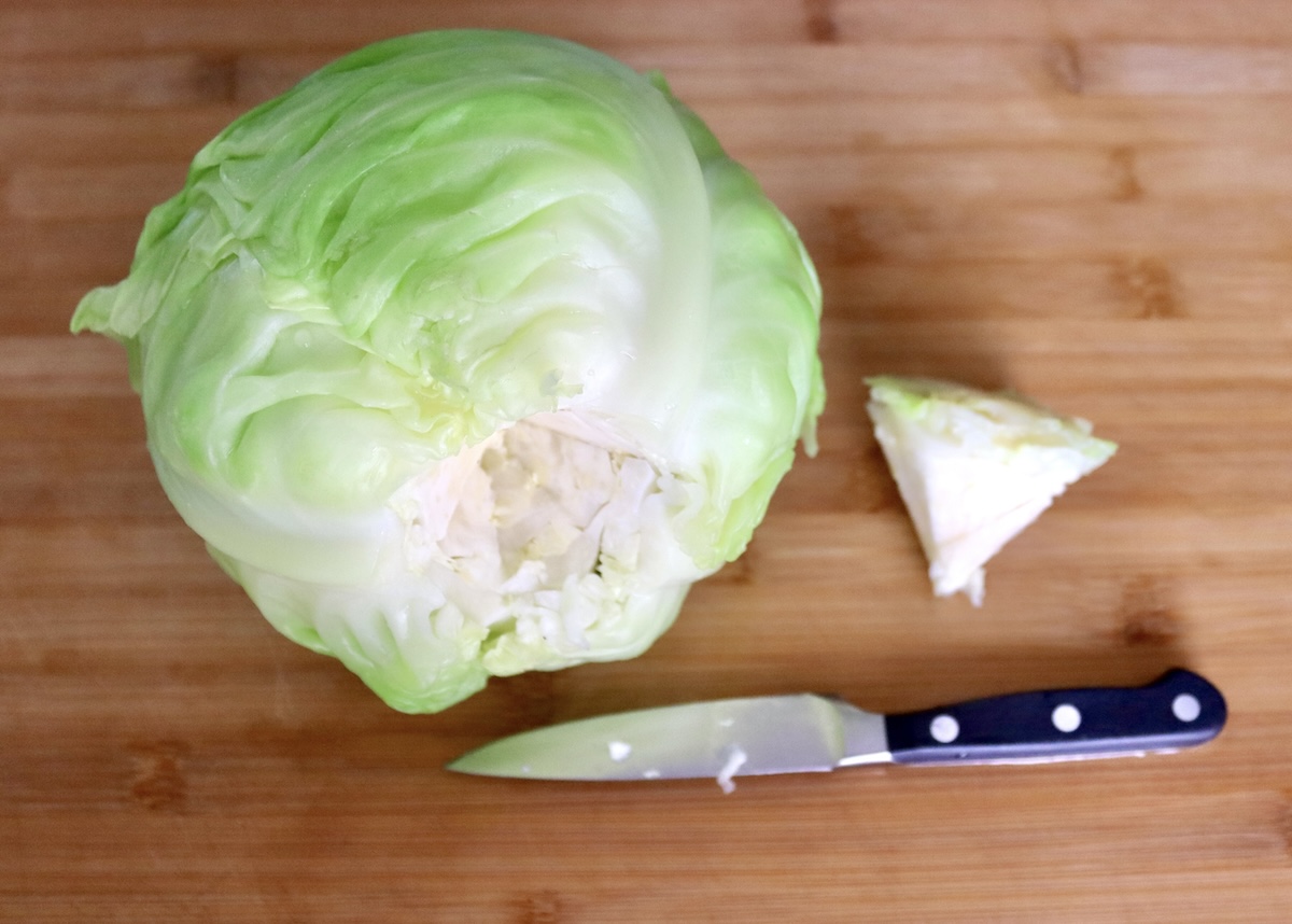 Salmon-and-Cabbage-Recipe A whole head of green cabbage with the root cut out, and sitting next to it with a paring knife.