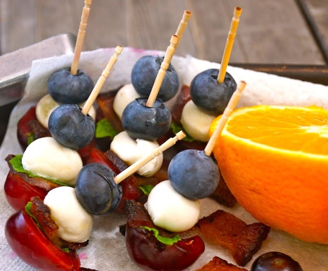 Mini Fruit Skewers on a paper towel with half of an orange.