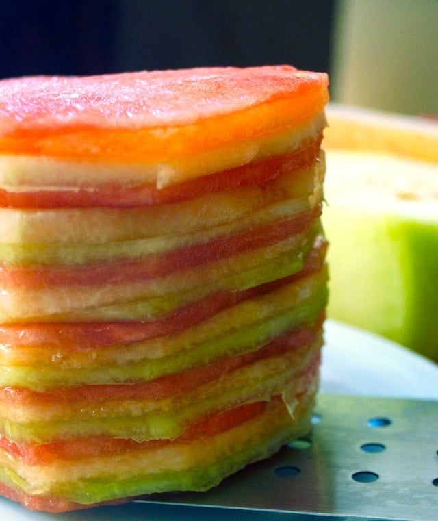 Close up of a stack of thinly sliced melon, in varying colors