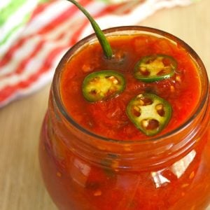 Spicy Serrano-Tomato Preservesin a round jar with serrano stem poking out.