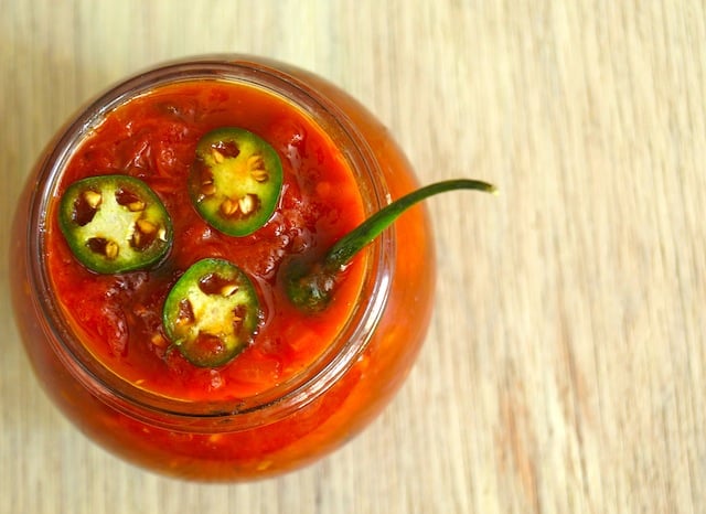 Top view of Sweet Tomato Preserves Recipe in a small jar with serrano slices on top