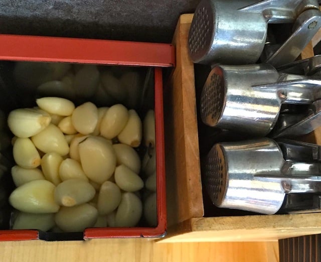 Fresh, whole garlic condiment and silver garlic presses on a table 