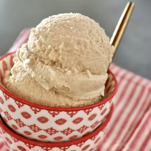 Two little stacked red and white bowls with a couple of scoops of root beer float ice cream and a gold spoon.