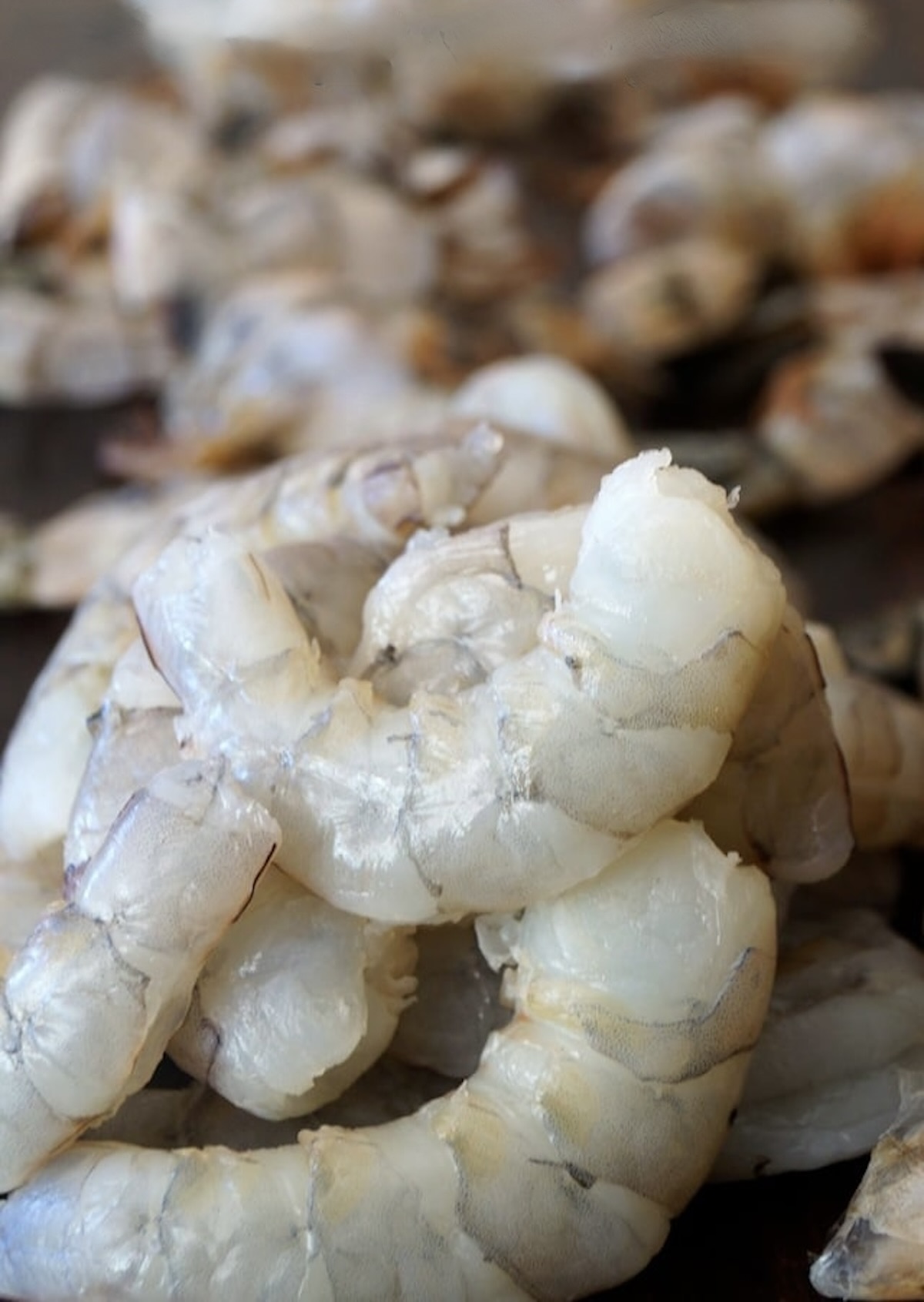 How-to-Peel-and-Devein-Shrimp Pile of peeled and deveined shrimp onblack background.