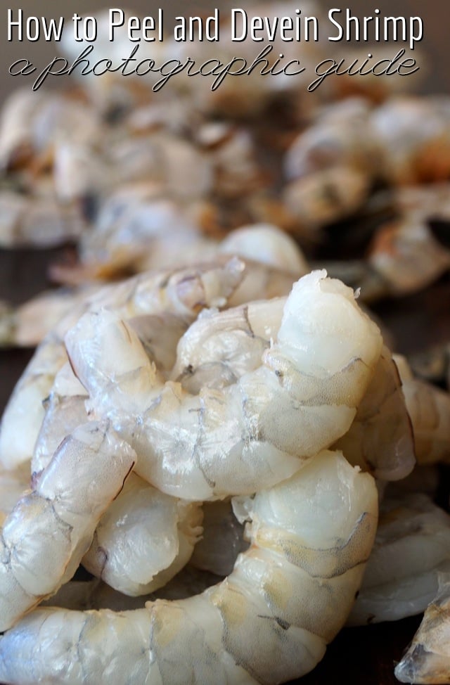 A pile of raw shrimp with shells behind them.