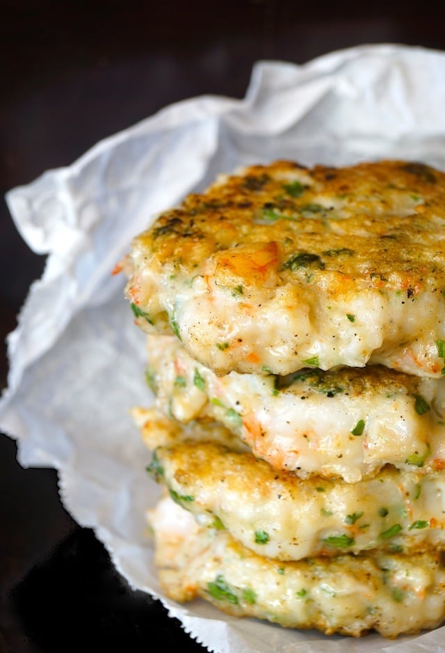 A stack of four shrimp burgers on what parchment paper.