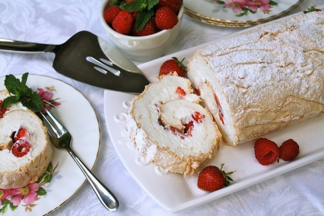 Summer Berry Meringue Roulade on white platter with fresh berries