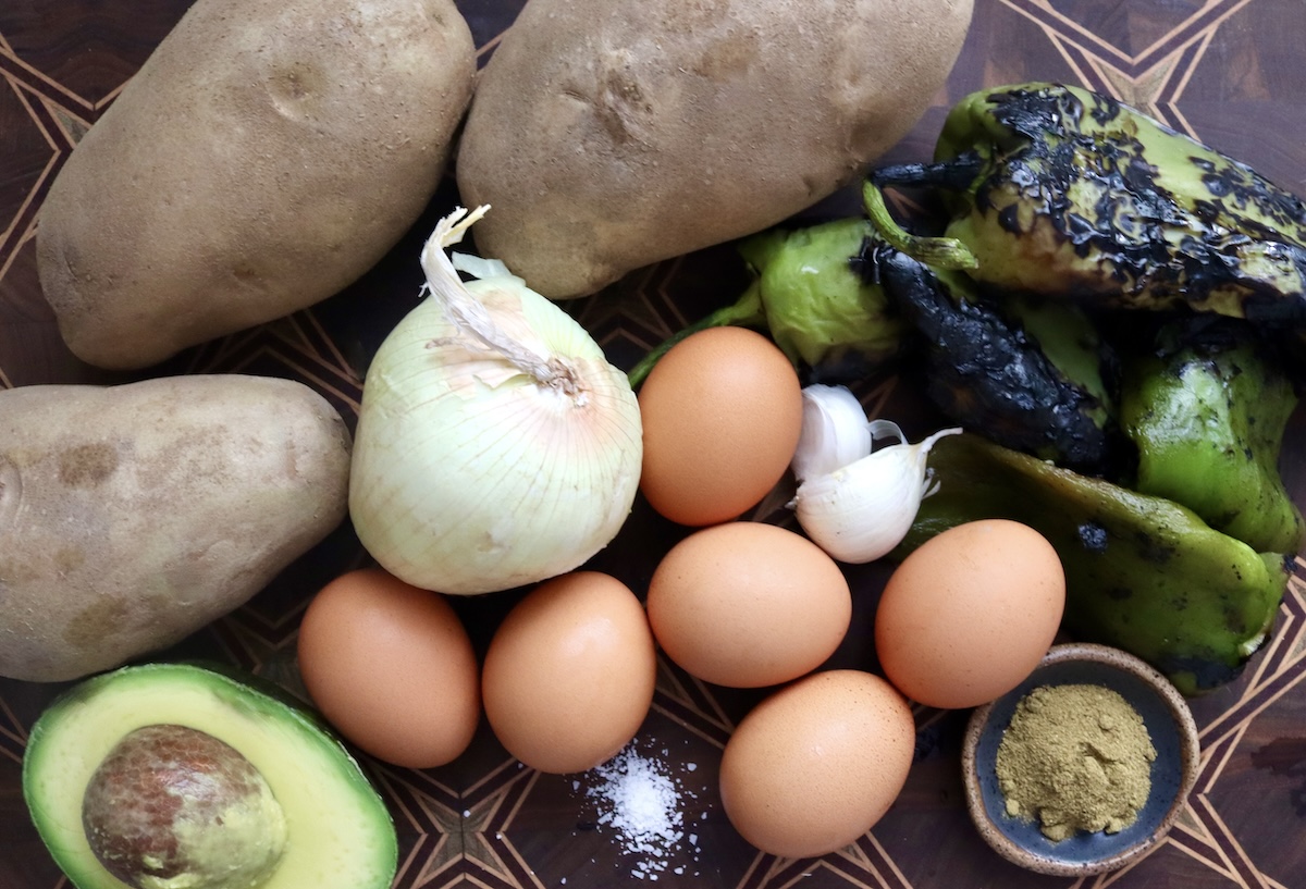 Poached-Egg-Double-Hatch-Hash-Browns Ingredients for Hatch Chile Hash Browns with Poached Eggs including: onion, eggs, garlic, roasted Hatch chiles, Russet potatoes, spices and an avocado.